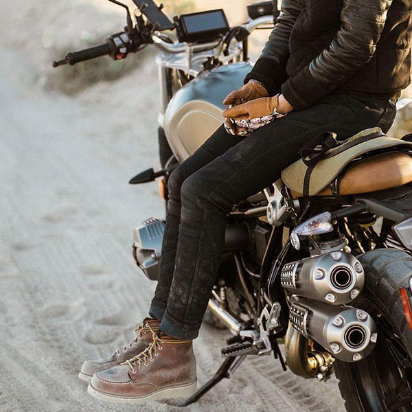woman sitting on her motorcycle on a dusty road
