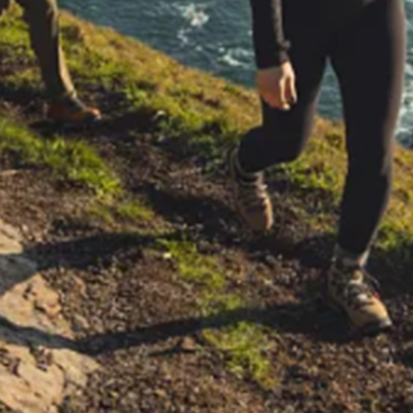 woman in hiking boots standing on a hill overlooking the water